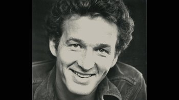 Movie still from “Stories We Tell” (2012), directed by Sarah Polley – Black and white photograph of a man smiling for the camera; Close Up shot, High angle