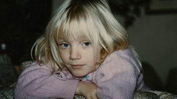 Movie still from “Stories We Tell” (2012), directed by Sarah Polley – A little girl with blonde hair wearing a pink sweater; Extreme Close Up shot, High angle