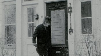 Movie still from “Stories We Tell” (2012), directed by Sarah Polley – An old man standing in front of a door; Wide shot, High angle