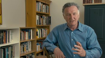 Movie still from “Stories We Tell” (2012), directed by Sarah Polley – An older man is sitting in front of a book shelf; Close Up shot, High angle
