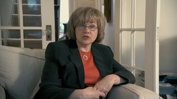 Movie still from “Stories We Tell” (2012), directed by Sarah Polley – A woman sitting on top of a couch in a living room; Close Up shot, Over the shoulder angle