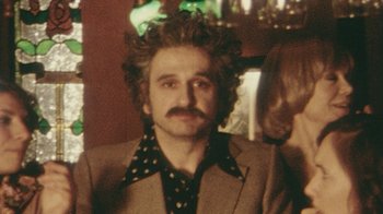 Movie still from “Stories We Tell” (2012), directed by Sarah Polley – A man in a brown suit and polka dot shirt; Close Up shot, High angle