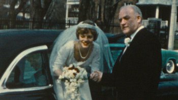 Movie still from “Stories We Tell” (2012), directed by Sarah Polley – An older man and a younger woman holding hands in front of a car; Close Up shot, High angle