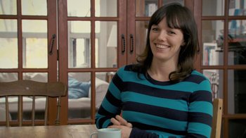 Movie still from “Stories We Tell” (2012), directed by Sarah Polley – A woman sitting at a table with a cup of coffee; Close Up shot, Over the shoulder angle