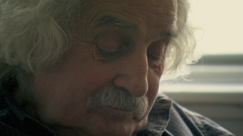 Movie still from “Stories We Tell” (2012), directed by Sarah Polley – An older man with a beard and mustache; Close Up shot, Over the shoulder angle