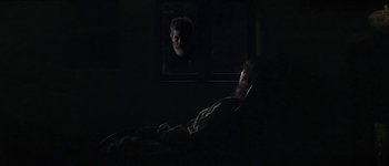 Movie still from “Story of My Death” (2013), directed by Albert Serra – A person in a dark room watching a television screen; Medium shot, Over the shoulder angle