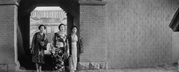 Movie still from “Story of a Prostitute” (1965), directed by Seijun Suzuki – A couple of women standing next to each other near a brick wall; Wide shot, Low angle