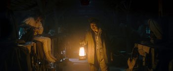 Movie still from “All Quiet on the Western Front” (2022), directed by Edward Berger – A man holding a lantern while standing in a dark room; Medium shot, Low angle