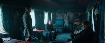 Movie still from “All Quiet on the Western Front” (2022), directed by Edward Berger – A man sitting in a chair in front of two other men; Wide shot, Low angle