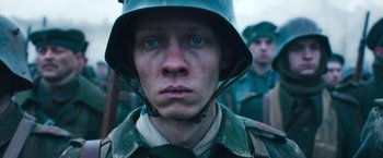Movie still from “All Quiet on the Western Front” (2022), directed by Edward Berger – A man wearing a helmet and looking into the camera; Close Up shot, Low angle