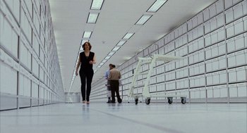 Movie still from “Stranger Than Fiction” (2006), directed by Marc Forster – A woman walking down a hallway with a cart in front of her; Wide shot, Low angle