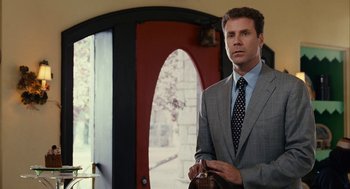 Movie still from “Stranger Than Fiction” (2006), directed by Marc Forster – A man in a suit and tie holding a purse; Medium shot, Over the shoulder angle