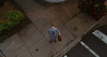 Movie still from “Stranger Than Fiction” (2006), directed by Marc Forster – A man in a suit holding a briefcase on the sidewalk; Extreme Wide shot, Overhead angle