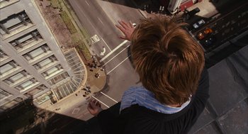 Movie still from “Stranger Than Fiction” (2006), directed by Marc Forster – A man standing in front of a large window; Wide shot, Overhead angle