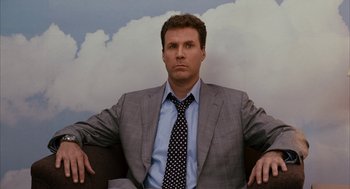 Movie still from “Stranger Than Fiction” (2006), directed by Marc Forster – A man wearing a suit and tie sitting in a chair; Medium shot, Low angle