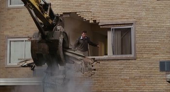 Movie still from “Stranger Than Fiction” (2006), directed by Marc Forster – A man standing on a balcony looking out of a window; Extreme Wide shot, Over the shoulder angle