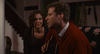 Movie still from “Stranger Than Fiction” (2006), directed by Marc Forster – A man and a woman sitting next to each other holding a guitar; Medium shot, Over the shoulder angle