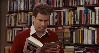 Movie still from “Stranger Than Fiction” (2006), directed by Marc Forster – A man reading a book in front of bookshelves; Close Up shot, High angle