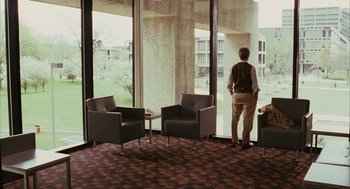 Movie still from “Stranger Than Fiction” (2006), directed by Marc Forster – A man standing in front of a window in a room; Wide shot, Over the shoulder angle