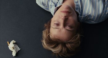 Movie still from “Stranger Than Fiction” (2006), directed by Marc Forster – A young man laying on the ground with his eyes closed; Close Up shot, Overhead angle