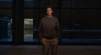 Movie still from “Stranger Than Fiction” (2006), directed by Marc Forster – A man standing in front of a building at night; Medium shot, Low angle
