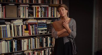 Movie still from “Stranger Than Fiction” (2006), directed by Marc Forster – A woman standing in front of a book shelf holding a book; Medium shot, Over the shoulder angle