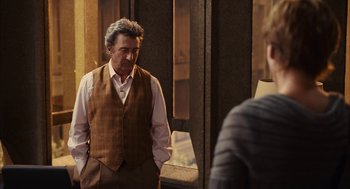 Movie still from “Stranger Than Fiction” (2006), directed by Marc Forster – An older man wearing a vest and a tie; Medium shot, Over the shoulder angle