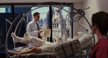 Movie still from “Stranger Than Fiction” (2006), directed by Marc Forster – A man in a white lab coat standing next to a bed; Wide shot, High angle
