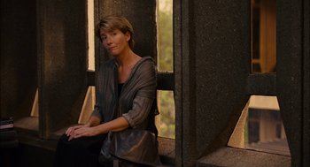 Movie still from “Stranger Than Fiction” (2006), directed by Marc Forster – A woman sitting on a window ledge looking out a window; Medium shot, Over the shoulder angle