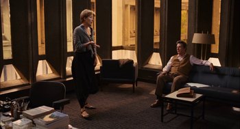 Movie still from “Stranger Than Fiction” (2006), directed by Marc Forster – A woman standing next to a man sitting in a chair; Wide shot, Over the shoulder angle
