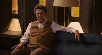 Movie still from “Stranger Than Fiction” (2006), directed by Marc Forster – A man sitting on top of a couch in front of a lamp; Medium shot, Over the shoulder angle