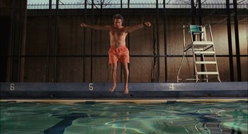 Movie still from “Stranger Than Fiction” (2006), directed by Marc Forster – A man jumping into a swimming pool with his arms outstretched; Wide shot, Overhead angle