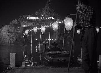 Movie still from “Strangers on a Train” (1951), directed by Alfred Hitchcock – A black - and - white photo of a tunnel of love at night; Extreme Wide shot, High angle