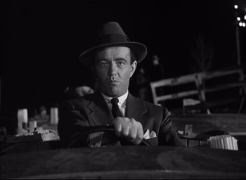 Movie still from “Strangers on a Train” (1951), directed by Alfred Hitchcock – A black and white photo of a man in a suit and tie; Medium shot, Low angle