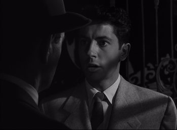 Movie still from “Strangers on a Train” (1951), directed by Alfred Hitchcock – A black and white photo of a man in a suit and tie looking at another man; Close Up shot, Over the shoulder angle