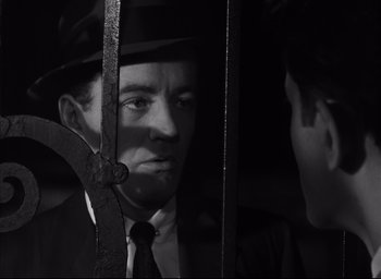 Movie still from “Strangers on a Train” (1951), directed by Alfred Hitchcock – A black and white photo of a man in a suit and tie; Close Up shot, Over the shoulder angle