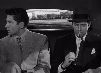 Movie still from “Strangers on a Train” (1951), directed by Alfred Hitchcock – Two men sitting in the back of a car smoking a cigarette; Medium shot, High angle