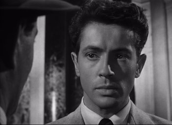 Movie still from “Strangers on a Train” (1951), directed by Alfred Hitchcock – A black and white photo of a man in a suit and tie; Close Up shot, Over the shoulder angle