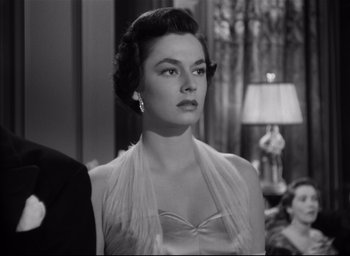 Movie still from “Strangers on a Train” (1951), directed by Alfred Hitchcock – An old photo of a woman in an evening gown; Close Up shot, Over the shoulder angle