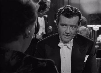 Movie still from “Strangers on a Train” (1951), directed by Alfred Hitchcock – A black and white photo of a man in a tuxedo; Medium shot, Over the shoulder angle