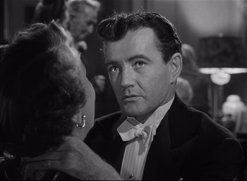 Movie still from “Strangers on a Train” (1951), directed by Alfred Hitchcock – An old photo of a man and a woman; Close Up shot, Over the shoulder angle