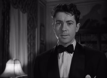 Movie still from “Strangers on a Train” (1951), directed by Alfred Hitchcock – A black and white photo of a man in a tuxedo; Close Up shot, Low angle