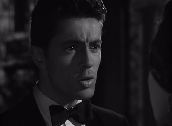 Movie still from “Strangers on a Train” (1951), directed by Alfred Hitchcock – Black and white photograph of a man wearing a suit and tie; Close Up shot, Over the shoulder angle