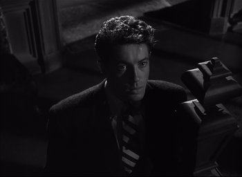 Movie still from “Strangers on a Train” (1951), directed by Alfred Hitchcock – A black and white photo of a man in a suit and tie; Close Up shot, High angle