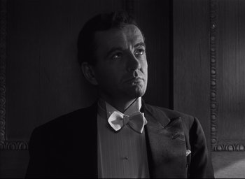 Movie still from “Strangers on a Train” (1951), directed by Alfred Hitchcock – Black and white photograph of a man in a suit and bow tie; Close Up shot, Low angle