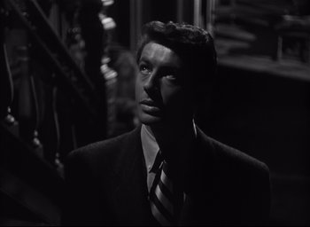 Movie still from “Strangers on a Train” (1951), directed by Alfred Hitchcock – A black and white photo of a man in a suit and tie; Close Up shot, Low angle