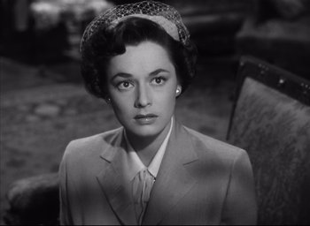 Movie still from “Strangers on a Train” (1951), directed by Alfred Hitchcock – A woman wearing a suit and hat in a black and white photo; Close Up shot, High angle