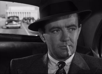 Movie still from “Strangers on a Train” (1951), directed by Alfred Hitchcock – A black and white photo of a man smoking a cigarette in the back of a car; Close Up shot, Low angle