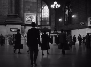 Movie still from “Strangers on a Train” (1951), directed by Alfred Hitchcock – A black and white photo of people walking in a train station; Extreme Wide shot, Low angle