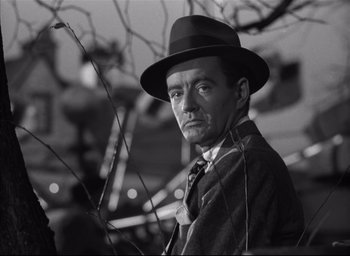Movie still from “Strangers on a Train” (1951), directed by Alfred Hitchcock – A black and white photo of a man wearing a hat; Close Up shot, Low angle